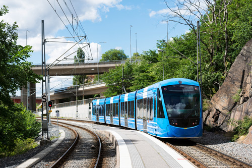 En blå spårvagn vid en järnvägsstation