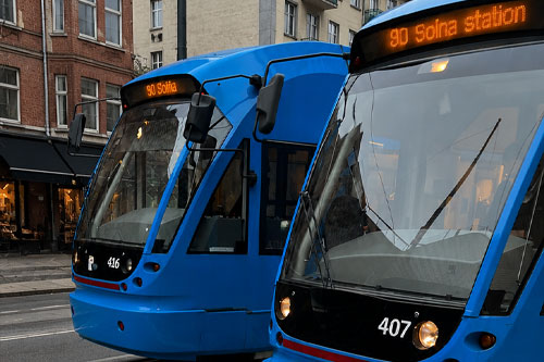 En blå spårvagn vid en järnvägsstation